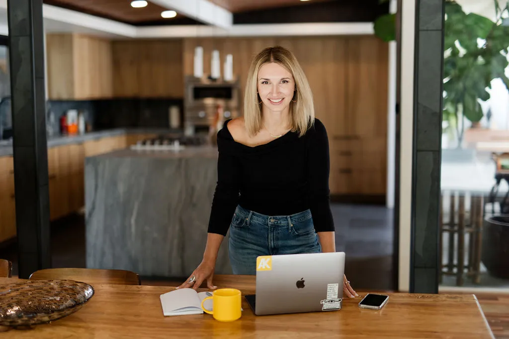 Akvile DeFazio standing at a table with her laptop and a yellow mug